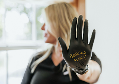Adorn technician with glove that says Booking Now